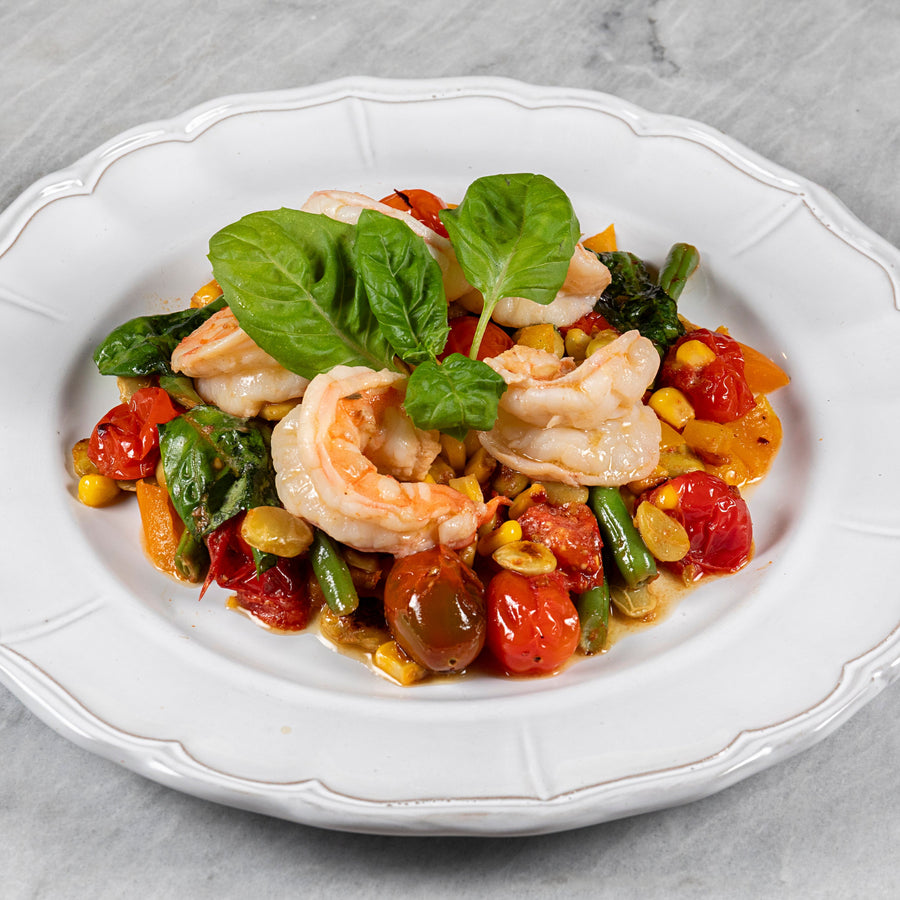 Plated dish of shrimp and vegetables on a marble surface