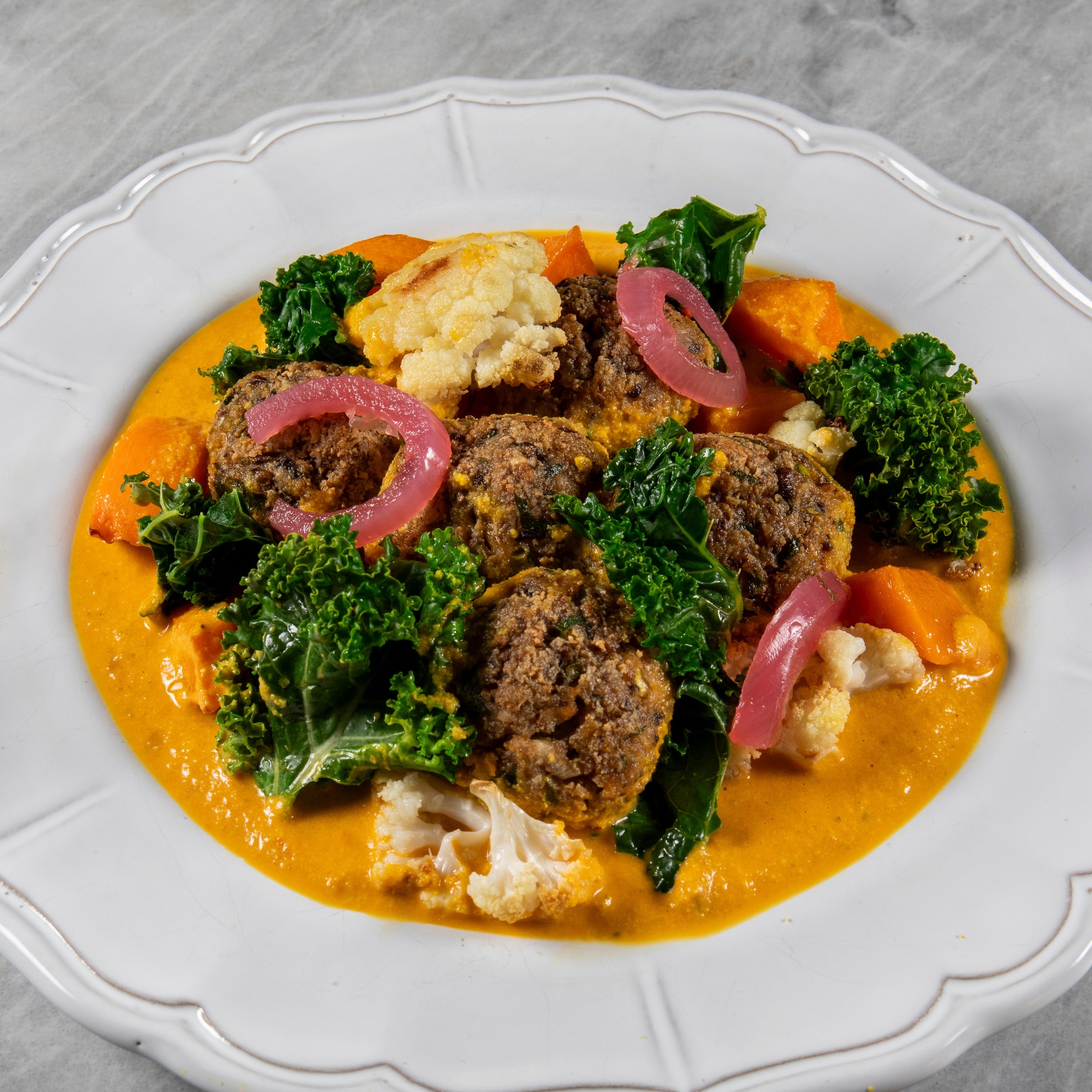 Plated dish with  kale, and vegetables on a marble background