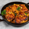 Skillet with chicken, chickpeas and vegetables on a marble surface
