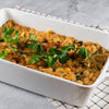 White rectangular baking dish of beans with breadcrumbs on a checkered cloth with a gray background